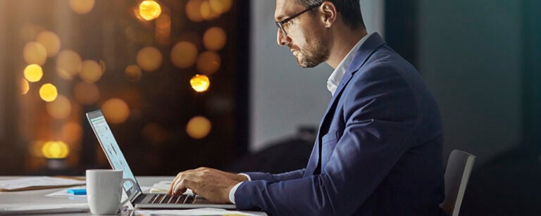 Man in suit typing on laptop in the evening