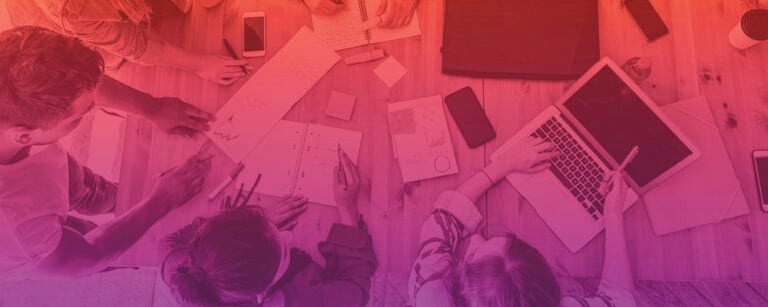 People working at cluttered table overhead view with color gradient