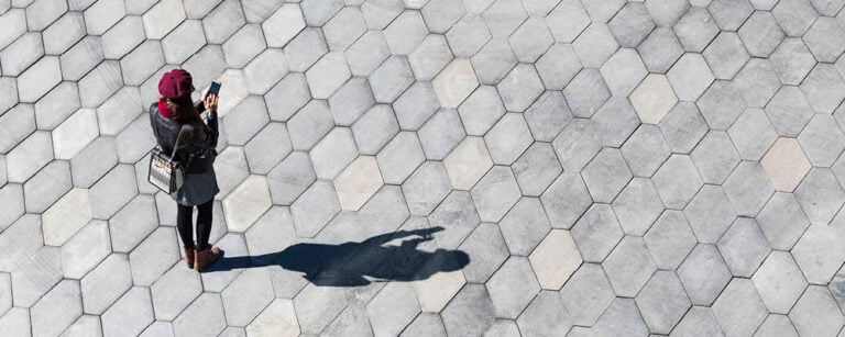 Woman on her phone with shadow on concrete