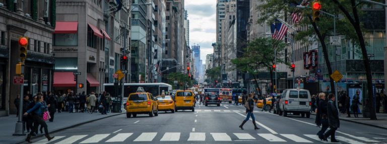 cabs and people walking in the middle of a busy city street