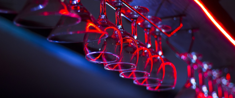 Neon wineglasses hanging from bar